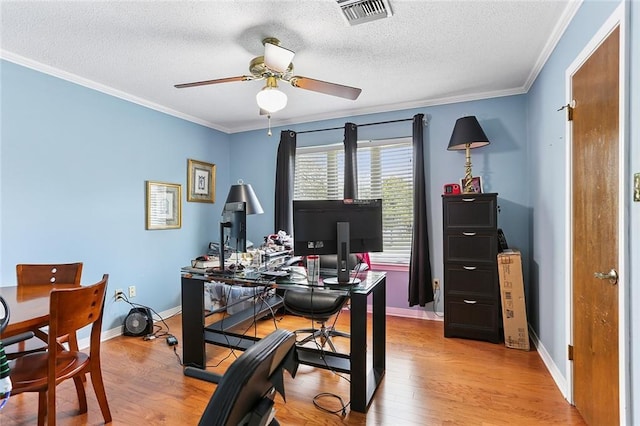 office featuring light wood-type flooring, visible vents, a textured ceiling, and ornamental molding