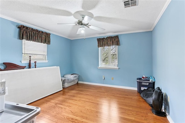 bedroom featuring baseboards, wood finished floors, visible vents, and ornamental molding