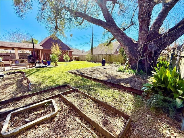 view of yard with a patio, a fenced backyard, and a garden