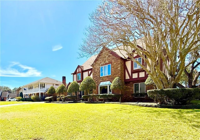 tudor house featuring a front yard and brick siding