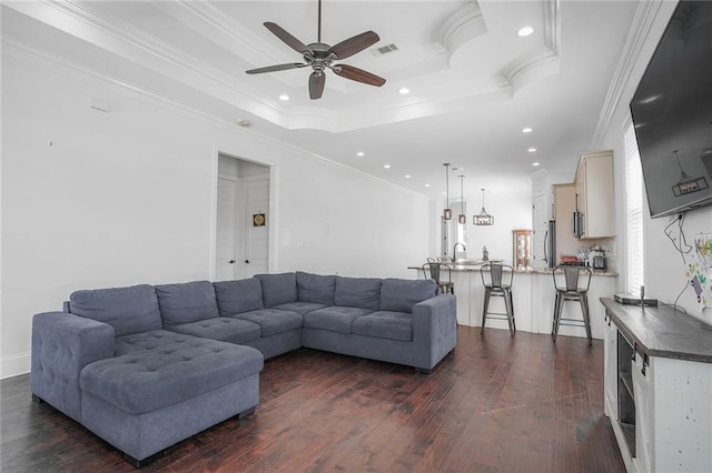 living area with visible vents, a raised ceiling, dark wood-style flooring, crown molding, and recessed lighting