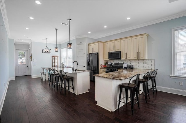 kitchen with range with gas stovetop, cream cabinetry, visible vents, and black fridge with ice dispenser