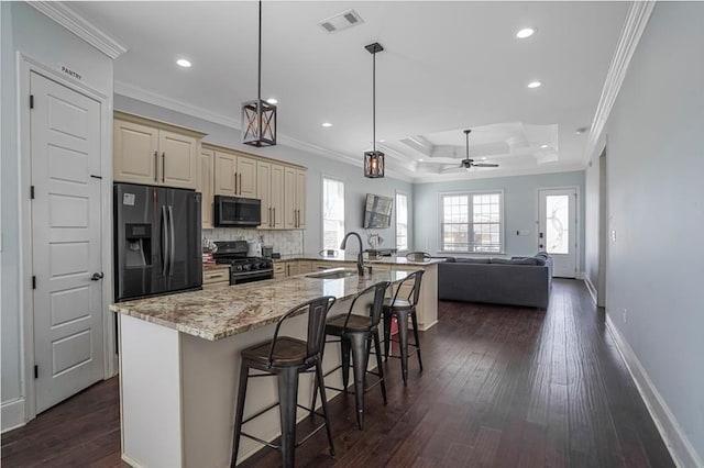 kitchen with dark wood finished floors, visible vents, cream cabinets, a sink, and black appliances