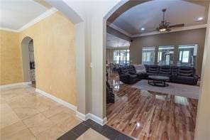 hall featuring arched walkways, ornamental molding, tile patterned flooring, and baseboards