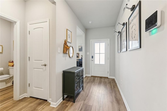 doorway with baseboards and light wood finished floors