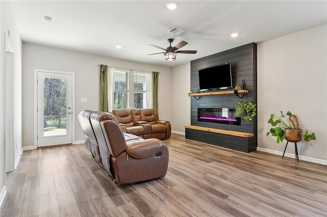 living room with a wealth of natural light, a fireplace, wood finished floors, and visible vents