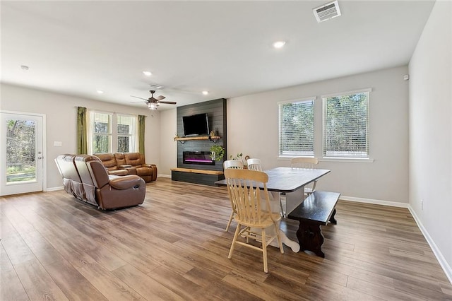 dining area featuring a large fireplace, a wealth of natural light, wood finished floors, and visible vents