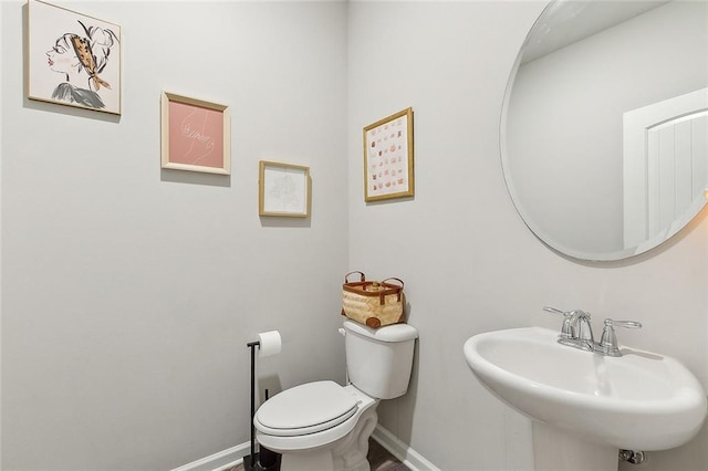 bathroom featuring toilet, baseboards, and a sink