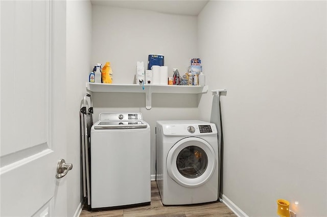 laundry area featuring light wood-type flooring, laundry area, washing machine and dryer, and baseboards