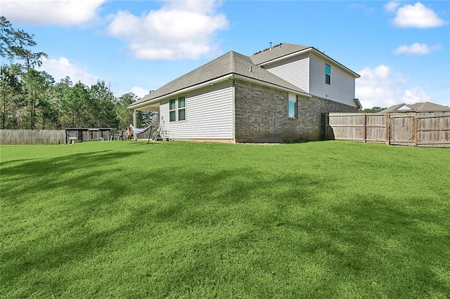 back of property featuring a fenced backyard, a yard, and brick siding