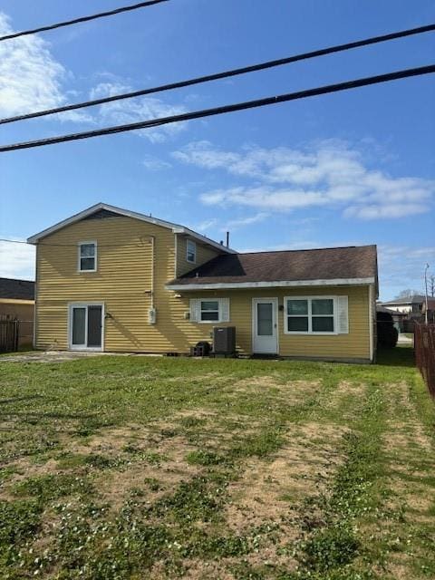 back of property featuring a lawn, fence, and central air condition unit