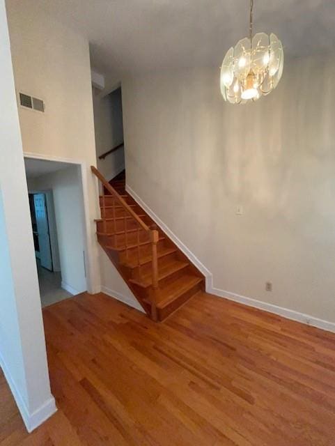 staircase with wood finished floors, visible vents, and baseboards