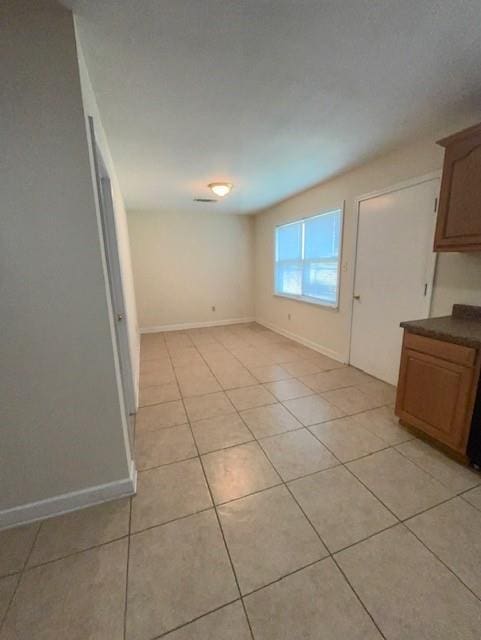 unfurnished dining area featuring light tile patterned flooring and baseboards