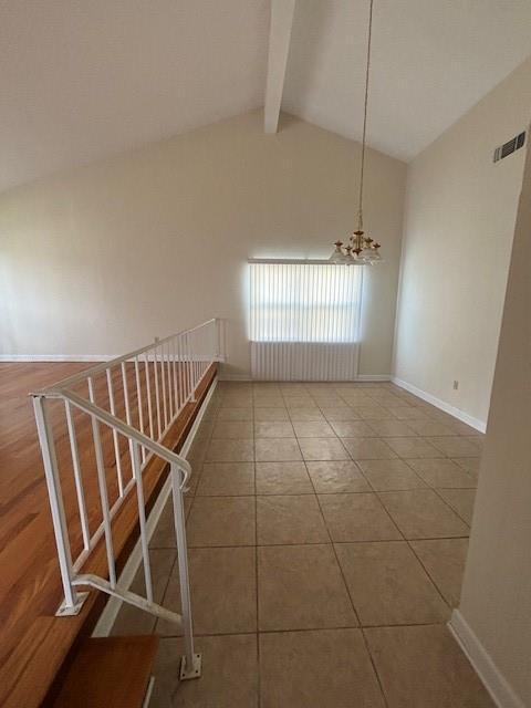 tiled empty room featuring a chandelier, beamed ceiling, visible vents, and baseboards