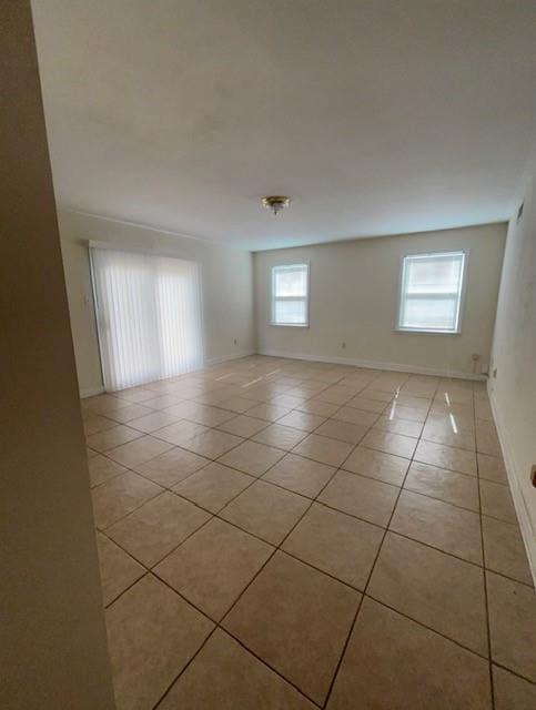 empty room featuring plenty of natural light, baseboards, and light tile patterned flooring