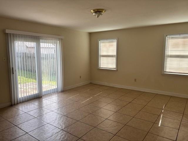 spare room featuring tile patterned flooring, a healthy amount of sunlight, and baseboards