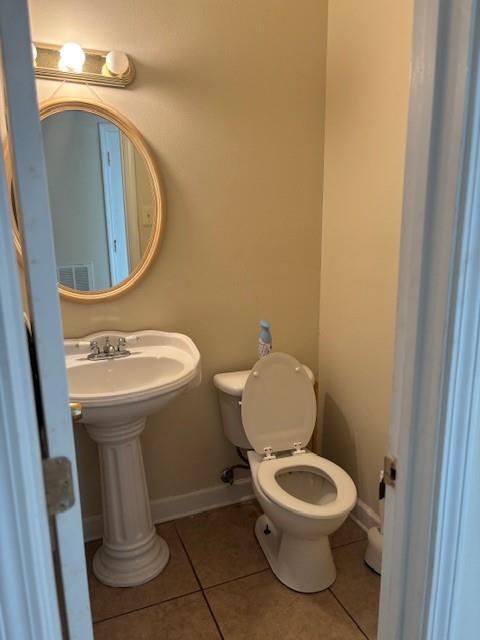 half bath with toilet, tile patterned flooring, visible vents, and baseboards