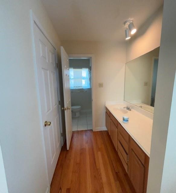 bathroom with toilet, baseboards, wood finished floors, and vanity