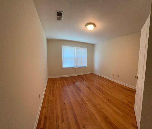 unfurnished room with light wood-style flooring, visible vents, and baseboards