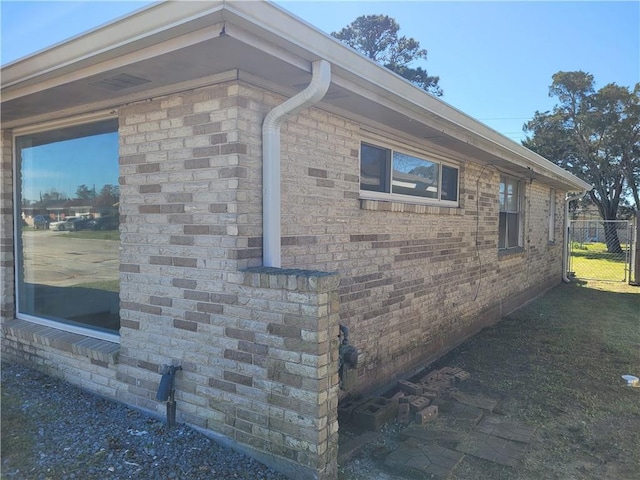 view of side of property featuring fence and brick siding