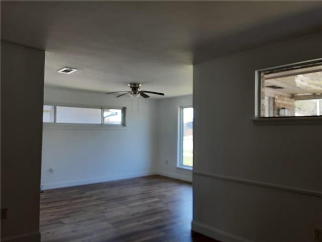 unfurnished room with ceiling fan, baseboards, and dark wood-type flooring