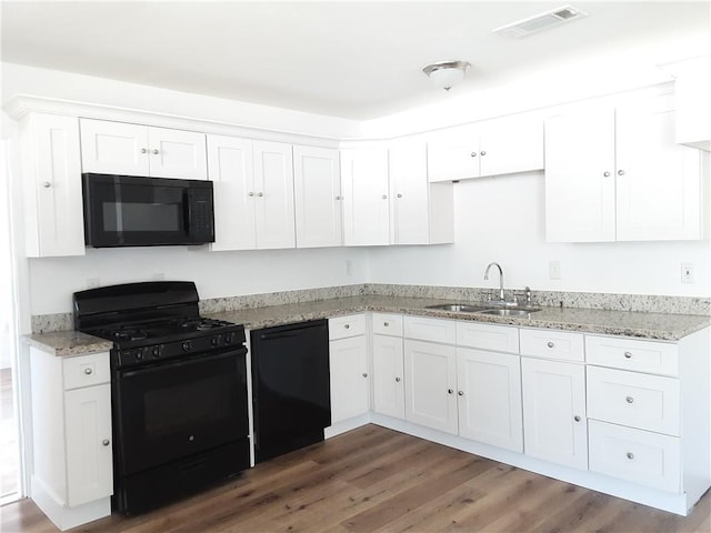 kitchen featuring visible vents, white cabinets, wood finished floors, black appliances, and a sink