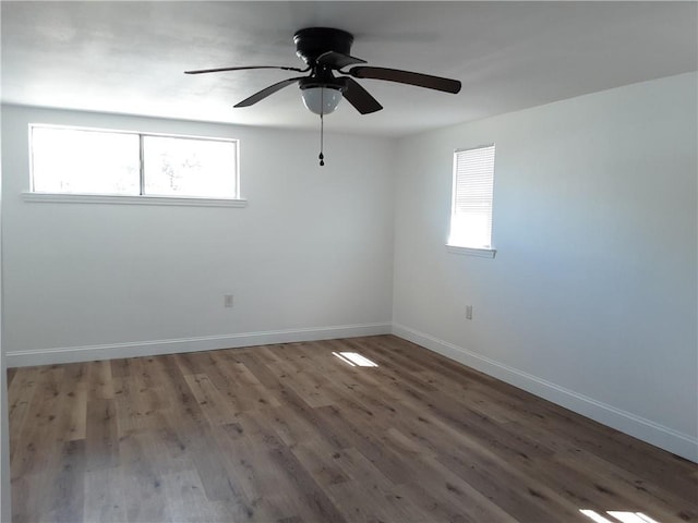 empty room featuring a wealth of natural light, ceiling fan, baseboards, and wood finished floors