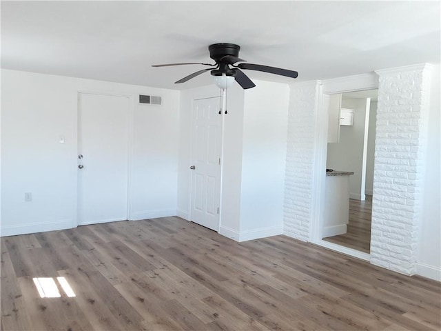 empty room featuring visible vents, ceiling fan, baseboards, and wood finished floors