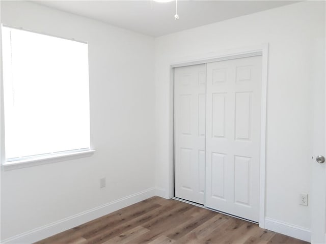 unfurnished bedroom with a closet, baseboards, and wood finished floors