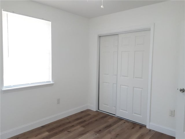 unfurnished bedroom featuring baseboards, a closet, and wood finished floors