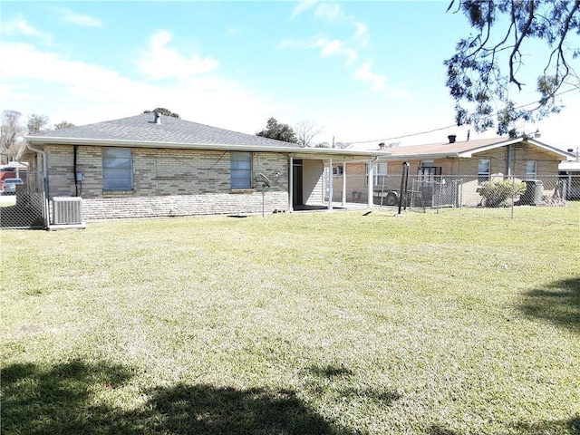 view of front of house with brick siding, roof with shingles, a front yard, fence, and cooling unit