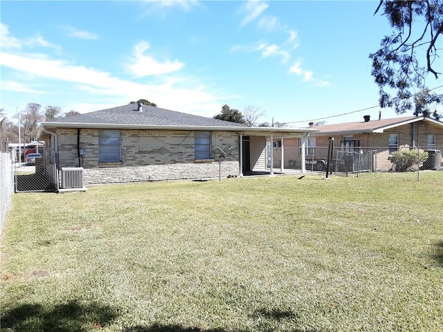 back of property featuring brick siding, fence, and a yard