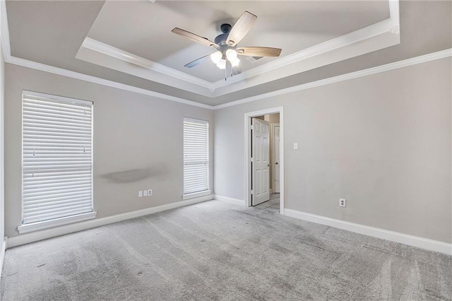 unfurnished room with carpet floors, a tray ceiling, a ceiling fan, and baseboards