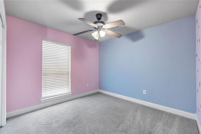 unfurnished room with carpet floors, a ceiling fan, and baseboards