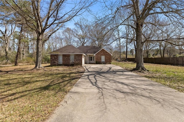 view of front of home featuring a front yard, brick siding, fence, and driveway