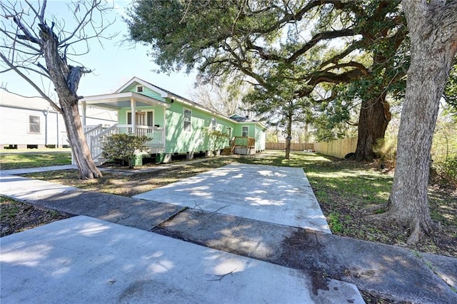 view of front of property with a front lawn, covered porch, fence, and concrete driveway