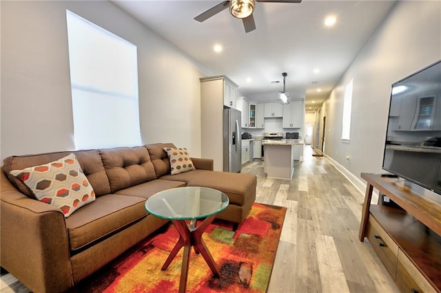 living area featuring light wood-style flooring, baseboards, ceiling fan, and recessed lighting