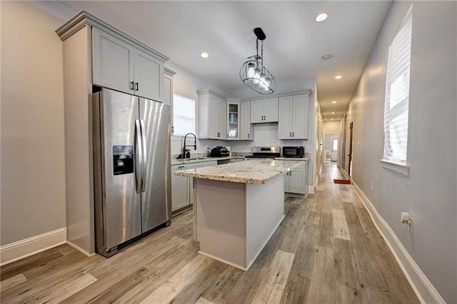 kitchen featuring a kitchen island, light stone countertops, stainless steel appliances, light wood-style floors, and recessed lighting