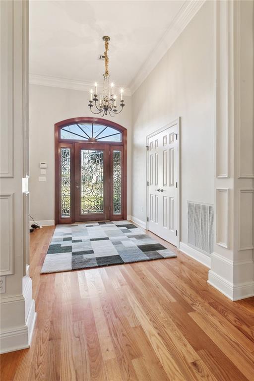 entryway featuring crown molding, wood finished floors, visible vents, and baseboards