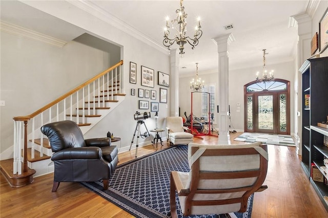 entrance foyer with wood finished floors, visible vents, ornate columns, stairs, and a notable chandelier