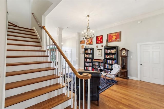 staircase with a chandelier, crown molding, baseboards, and wood finished floors