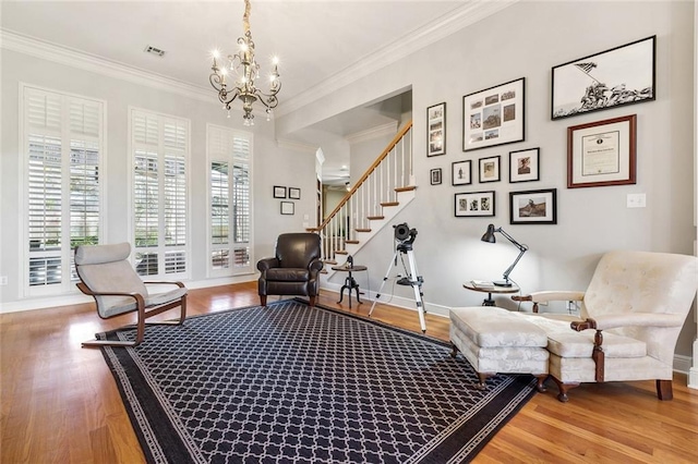 living area featuring wood finished floors, baseboards, visible vents, ornamental molding, and stairs