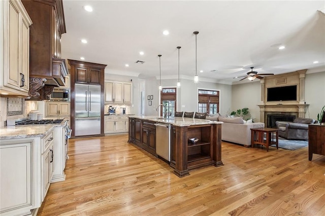 kitchen with dark brown cabinets, open floor plan, built in appliances, and a sink