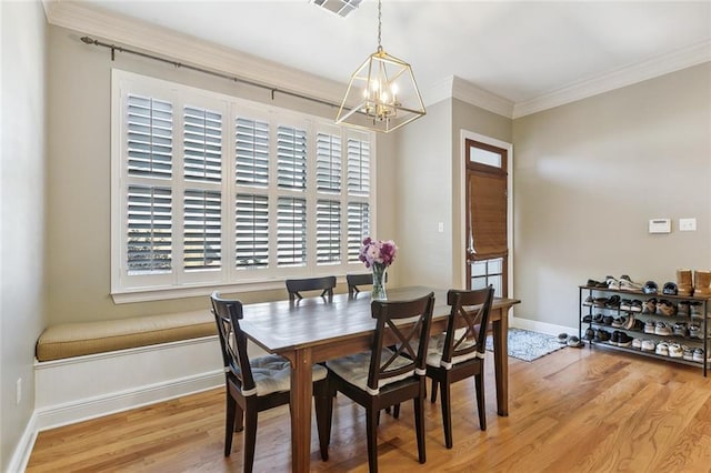 dining space featuring light wood finished floors, a notable chandelier, crown molding, and baseboards