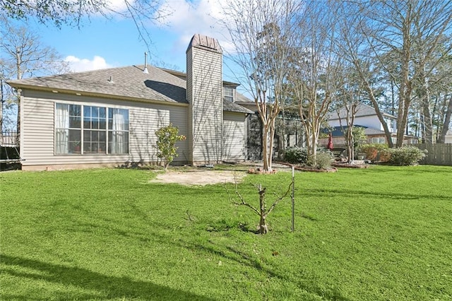 rear view of house featuring a lawn, a chimney, a patio, and fence