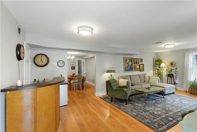 living room with light wood-style flooring, visible vents, and baseboards