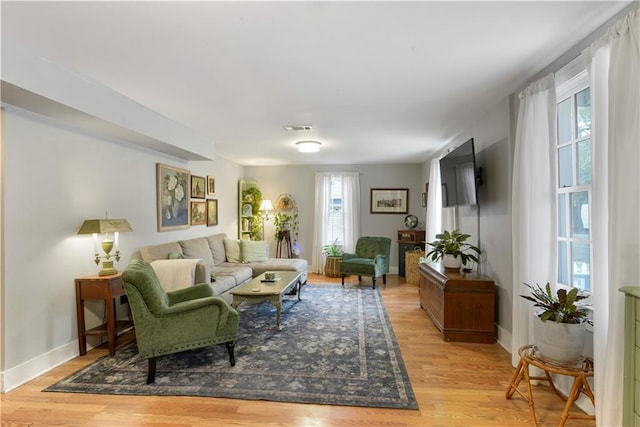 living area featuring visible vents, light wood-style flooring, and baseboards