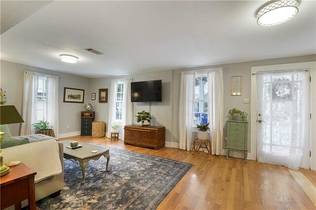 living area featuring visible vents, baseboards, and wood finished floors