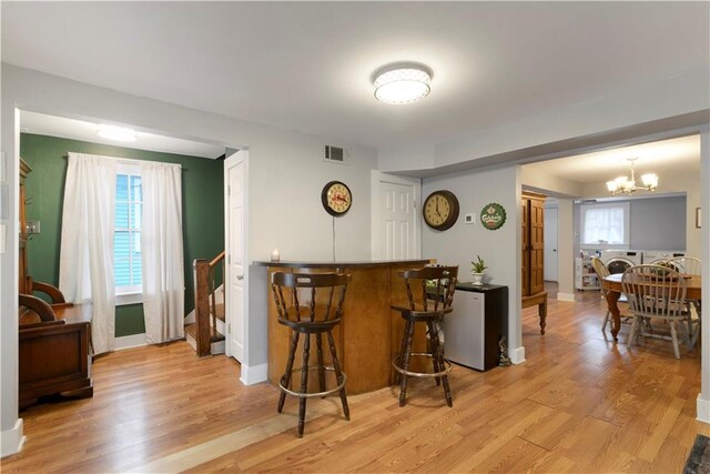 bar featuring light wood finished floors, stairway, washing machine and clothes dryer, and a notable chandelier