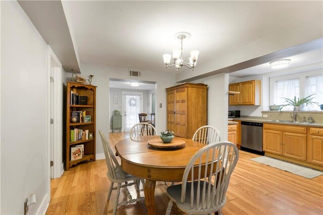 dining room featuring light wood-type flooring, visible vents, a notable chandelier, and baseboards